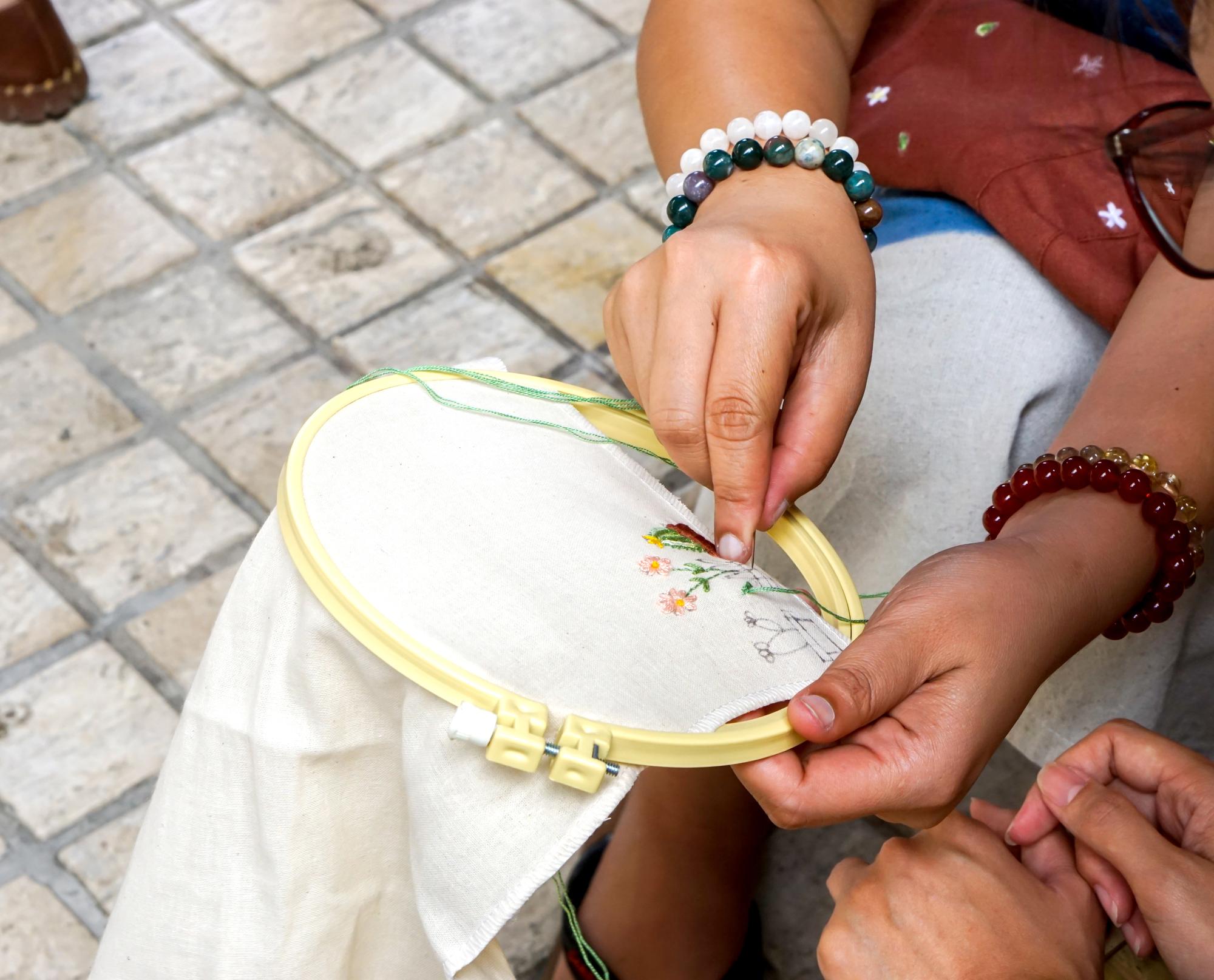 Instructor demonstrating needlework on hoop